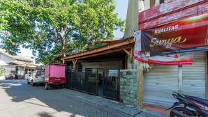 A street view with a parked car, a motorcycle, and a building with a closed shutter. - OYO Life 94040 Agung Home Stay (Surabaya)