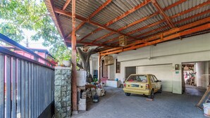 A covered parking area with a yellow car parked inside. - OYO Life 94040 Agung Home Stay (Surabaya)
