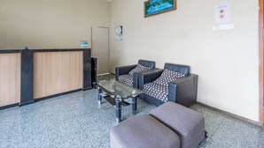 A reception area with a reception desk, two sofas, a glass coffee table, and a clock on the wall. - OYO Life 94040 Agung Home Stay (Surabaya)