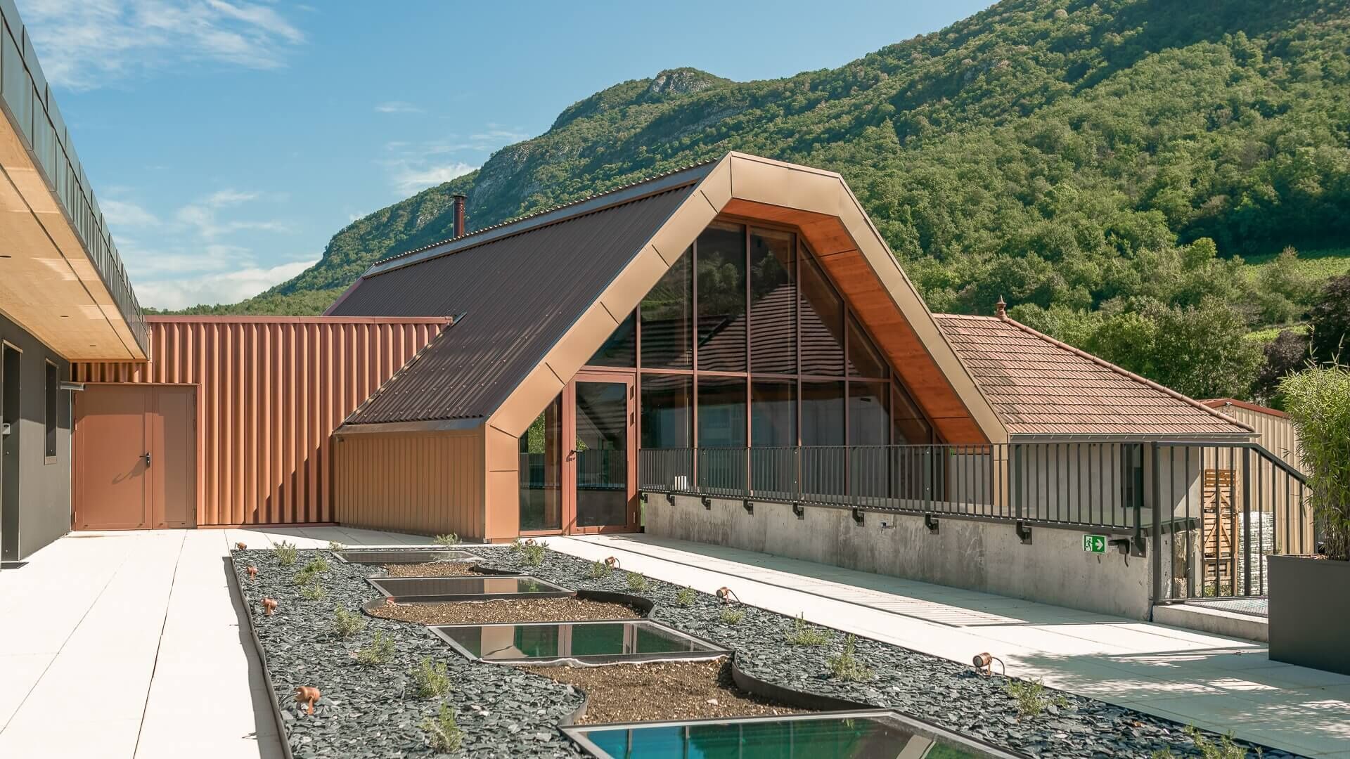 Ein modernes Haus mit geneigtem Dach, großen Fenstern und einem Swimmingpool.