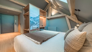Un dormitorio con una cama grande, un armario de madera y vistas a un paisaje nevado a través de una ventana.