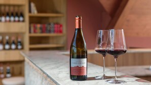Una botella de vino y dos copas sobre una encimera de mármol.