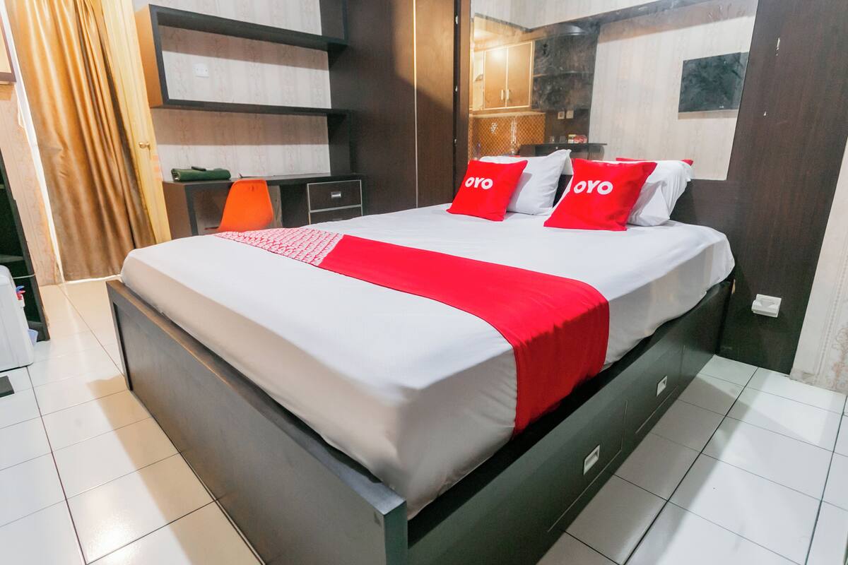 A modern hotel room with a large bed, a nightstand, a desk, and a wardrobe.