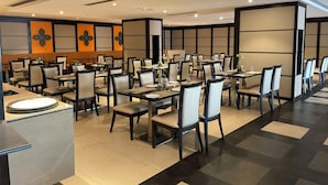 A spacious dining area with multiple tables and chairs, featuring a modern design with geometric wall patterns and recessed lighting. - V Club Sohna Road (Gurugram)