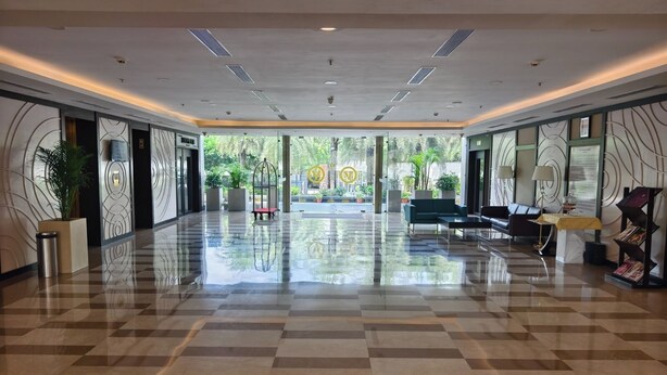 A spacious lobby with a checkered floor, seating area, and a view of the outdoors. - V Club Sohna Road (Gurugram)