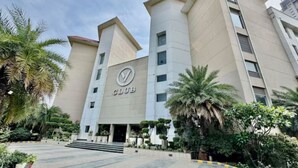 A modern building with a prominent 'CLUB' sign, featuring a geometric facade and a landscaped entrance area. - V Club Sohna Road (Gurugram)