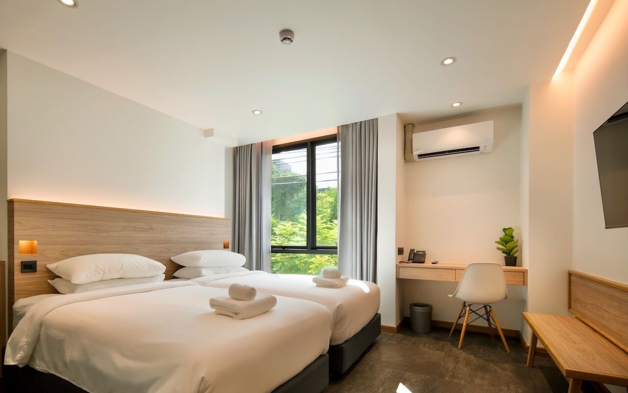 Een moderne hotelkamer met twee bedden, een bureau, een stoel en een televisie.