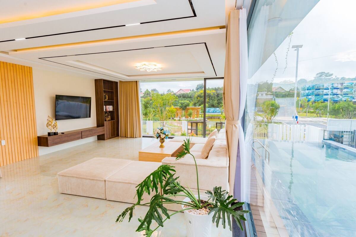 Uma sala de estar moderna com uma televisão grande, um sofá e um vaso de planta.