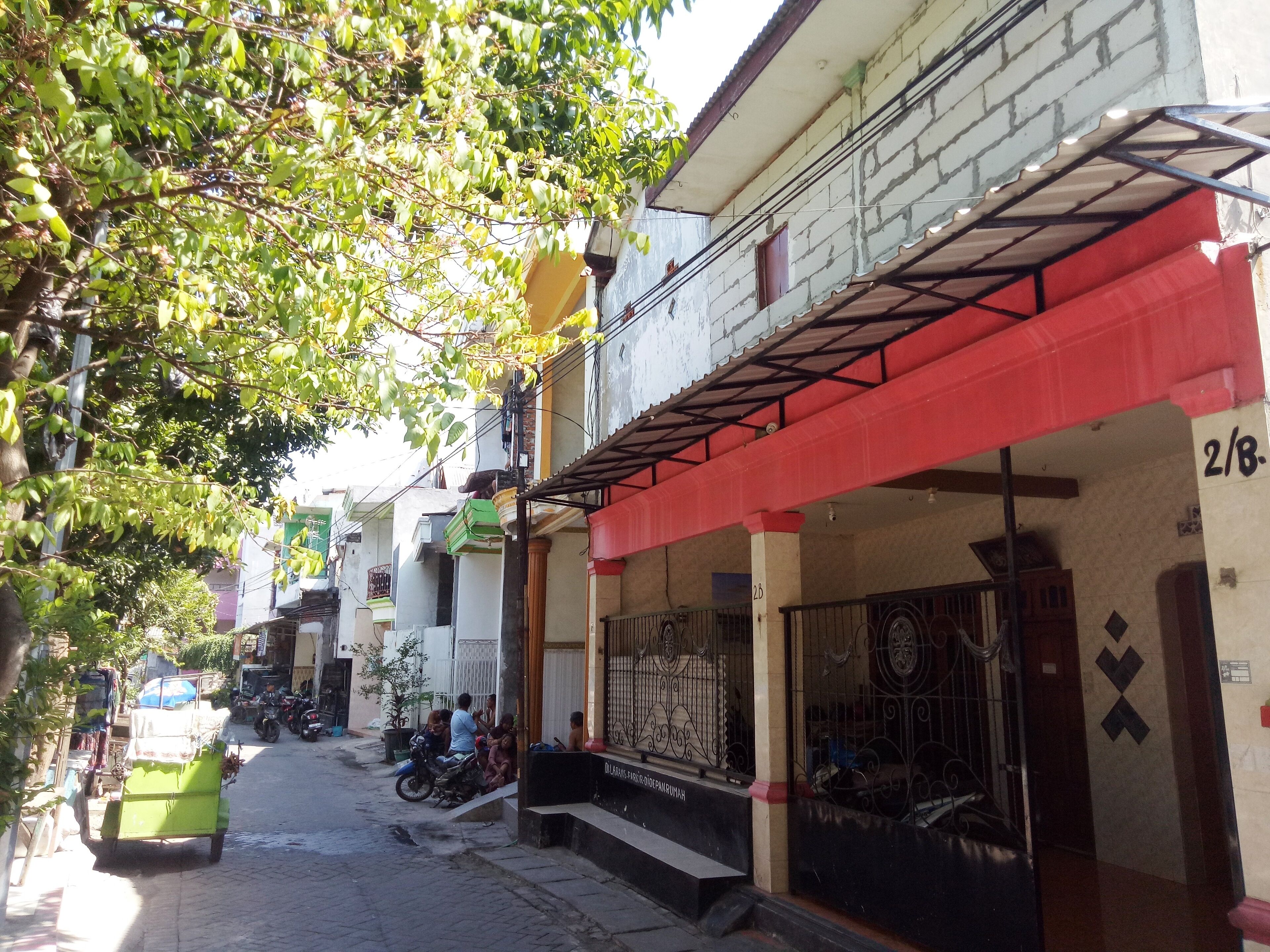A narrow street lined with multi-story buildings, some with balconies and awnings.