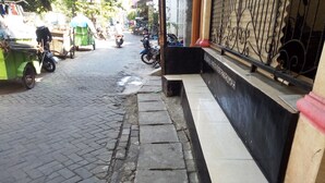 Rua pavimentada com um banco e uma parede preta com texto branco.