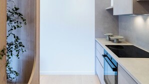Eine moderne Küche mit Holzschränken, einem eingebauten Backofen und einer Arbeitsfläche mit Spüle.
