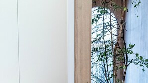 Ein modernes Interieur mit einem Holzregal, einem kleinen runden Holztisch und einem Blumentopf mit grünen Blättern.