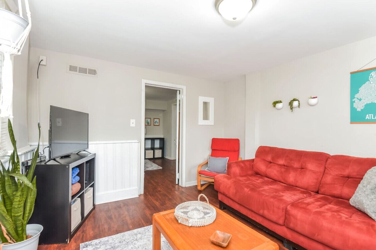 A living room with a red sofa, a television, and a small table with a basket.