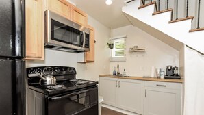 Een keuken met een kookplaat, oven, magnetron en houten keukenkastjes.