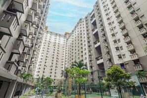 Um edifício residencial alto, com várias varandas e um pátio com vegetação.