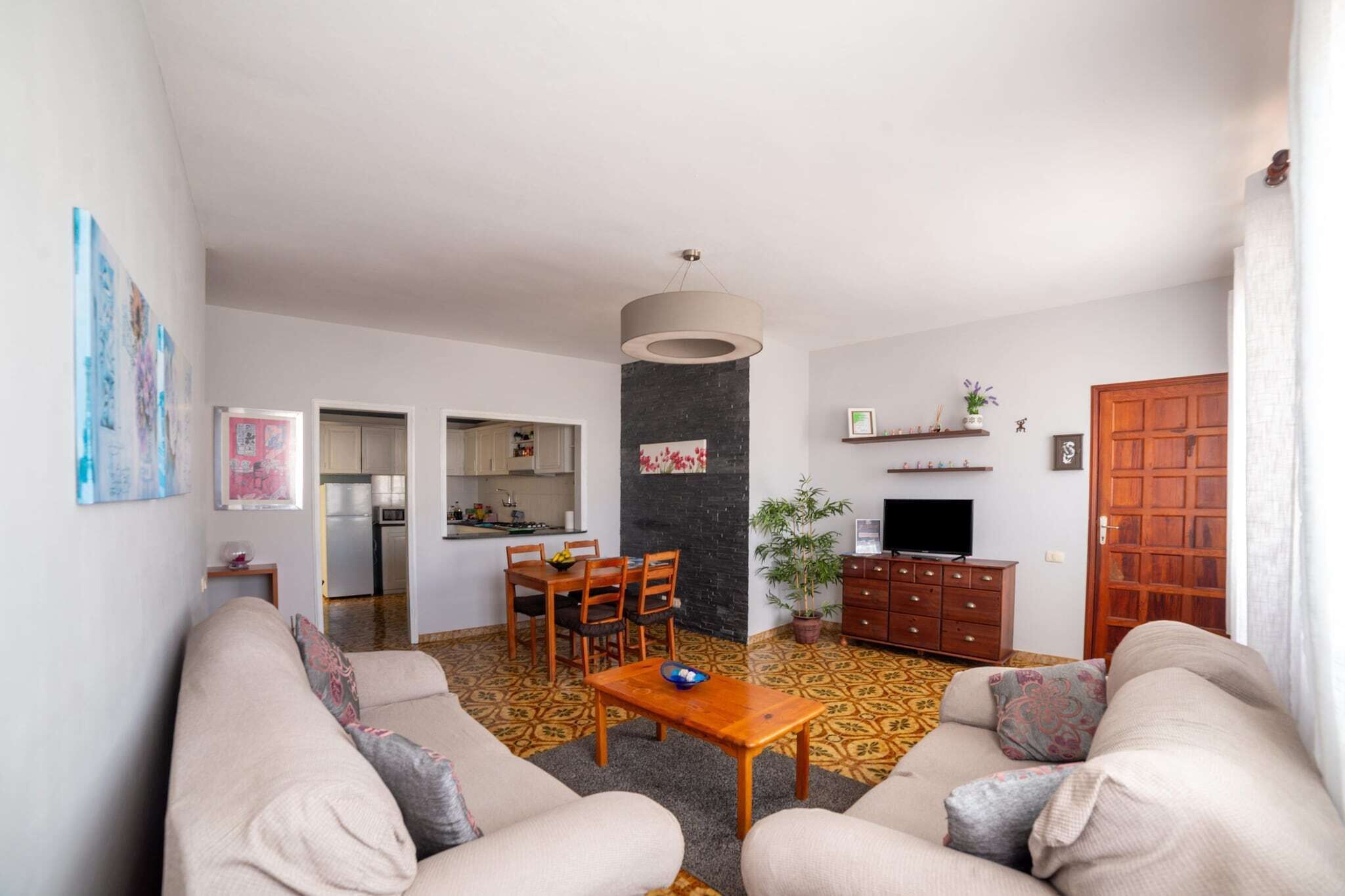Una sala de estar con un juego de sofá, una mesa de comedor y una cocina al fondo.