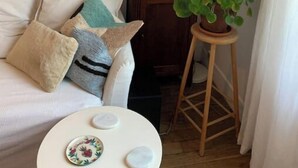 A cozy living room with a sofa, a small round table, and a potted plant. - Montreuil City, Artists (Montreuil)