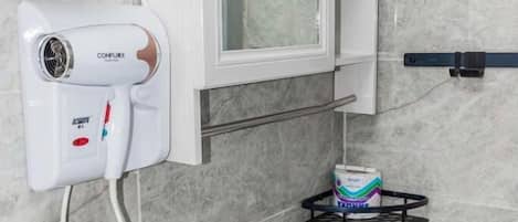 A bathroom with a white sink, a towel rack, a mirror, a hairdryer, and a soap dispenser.