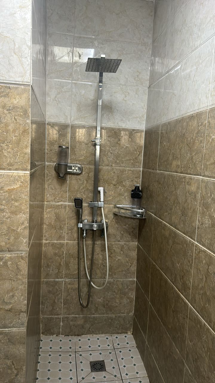 A shower area with a handheld showerhead, a wall-mounted faucet, and a control panel.