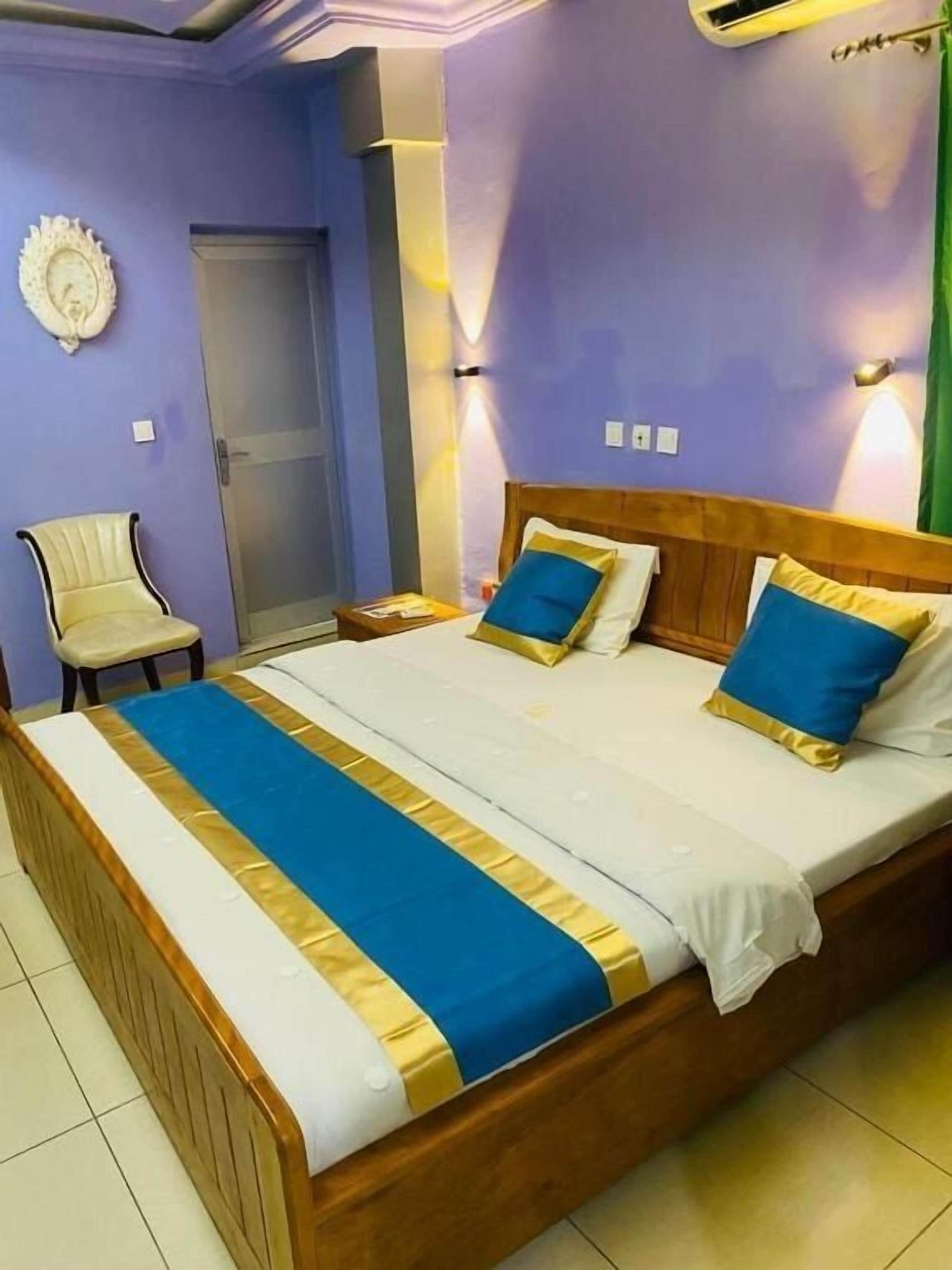 Una camera d'albergo con un letto grande, una sedia e una porta.