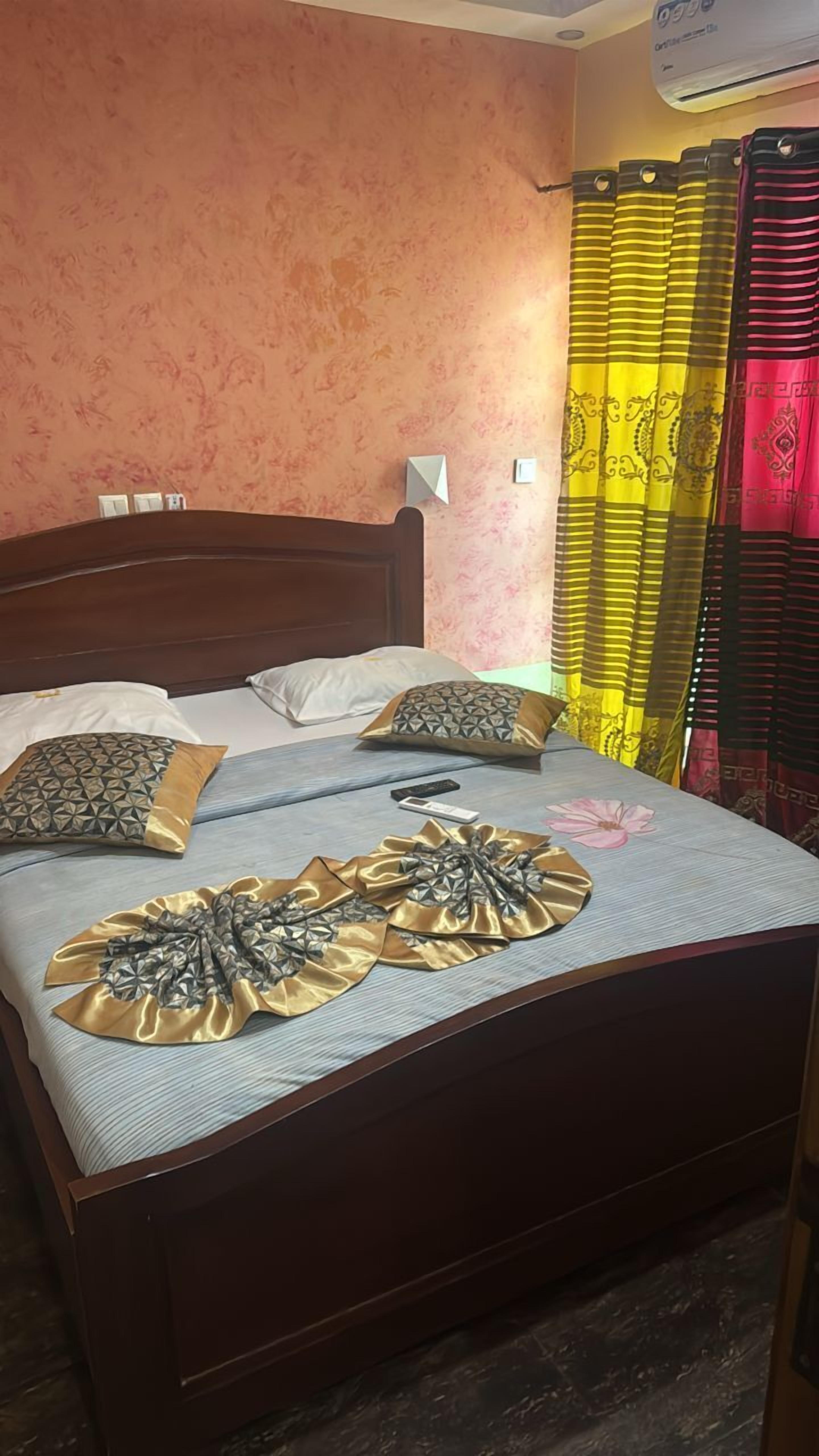 A neatly made bed with pillows, a remote control, and a decorative fabric on the bedspread.