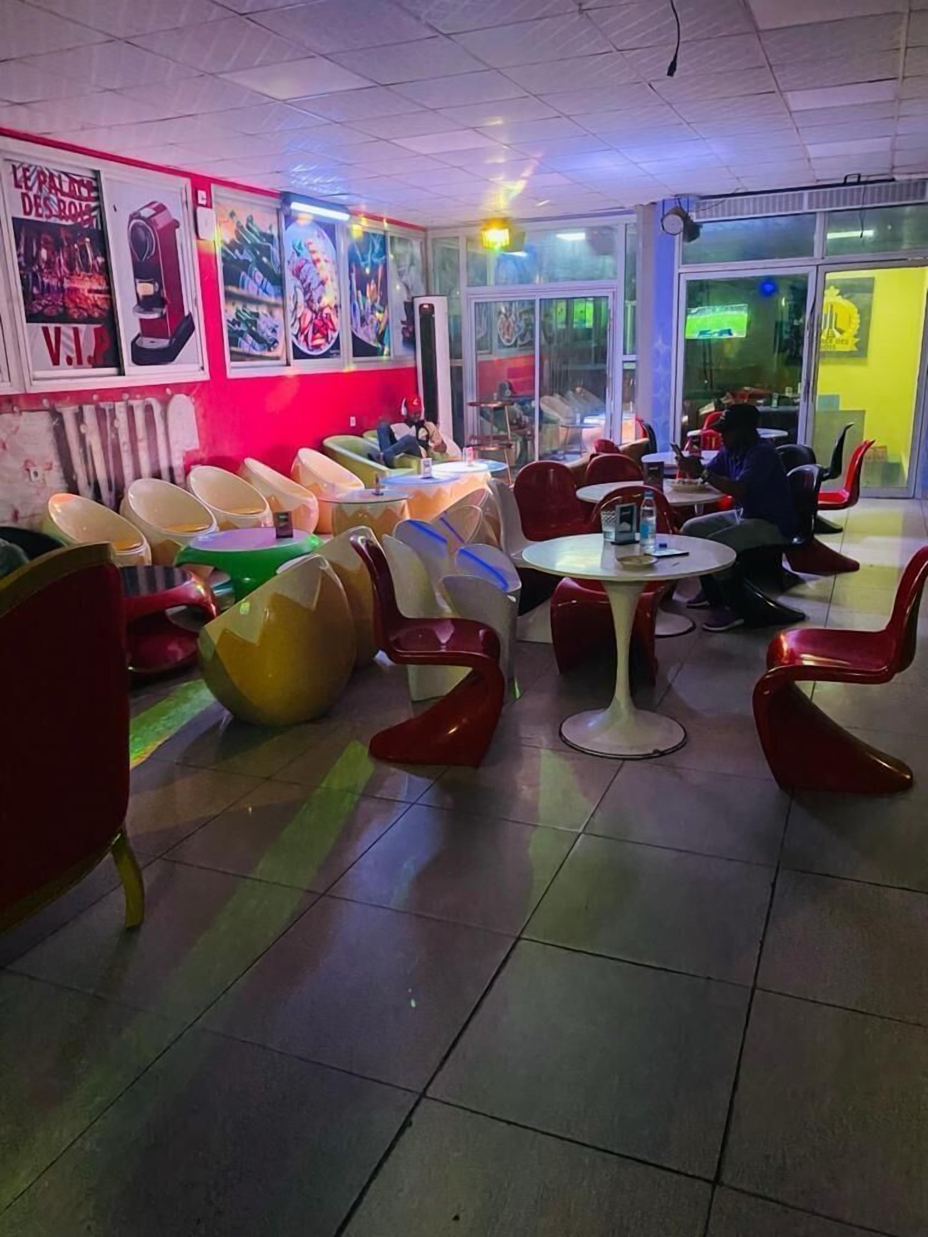 Een restaurant met kleurrijke stoelen en tafels, een betegelde vloer en posters aan de muur.