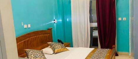 A bedroom with a wooden bed, a ceiling fan, and a wall-mounted air conditioner.