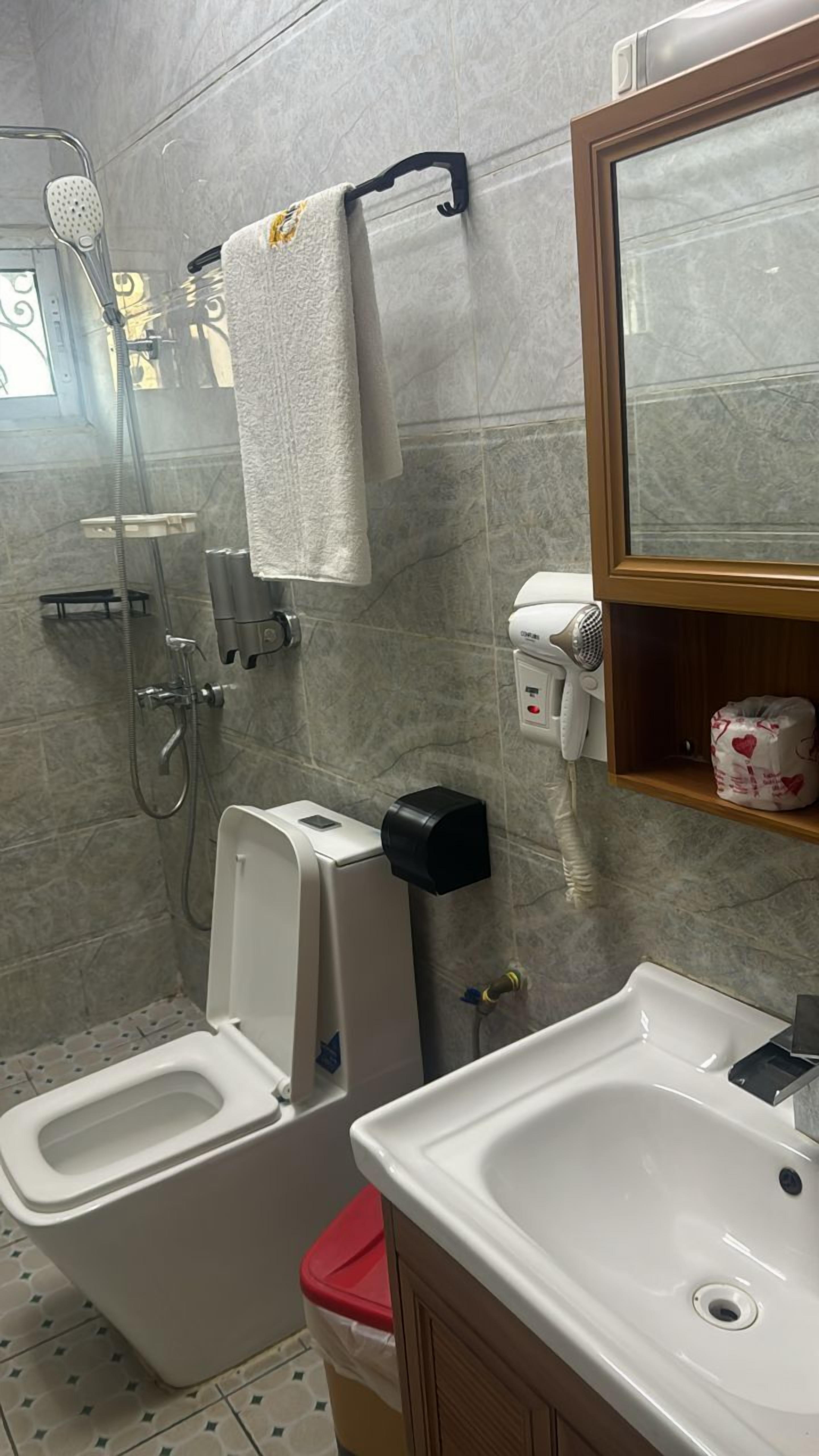 A bathroom with a shower, toilet, sink, and a towel hanging on a rack.