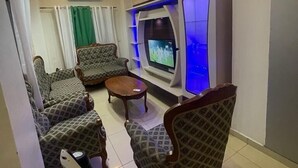Ein Wohnzimmer mit gemusterten Sofas, einem Couchtisch und einem Fernseher.