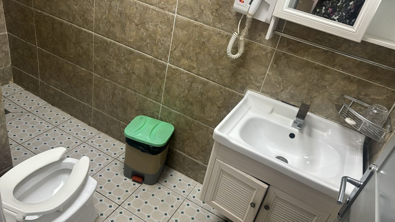 A bathroom with a toilet, sink, and trash bin.