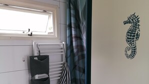 A bathroom with a white sink, a towel rack with multiple towels, a radiator, a toilet, and a seahorse decal on the wall. - Tinyhaus "carpe Diem" (Dirkshorn)
