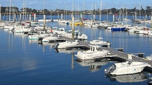 Una marina con diverse imbarcazioni ormeggiate, acqua calma e cielo azzurro terso.