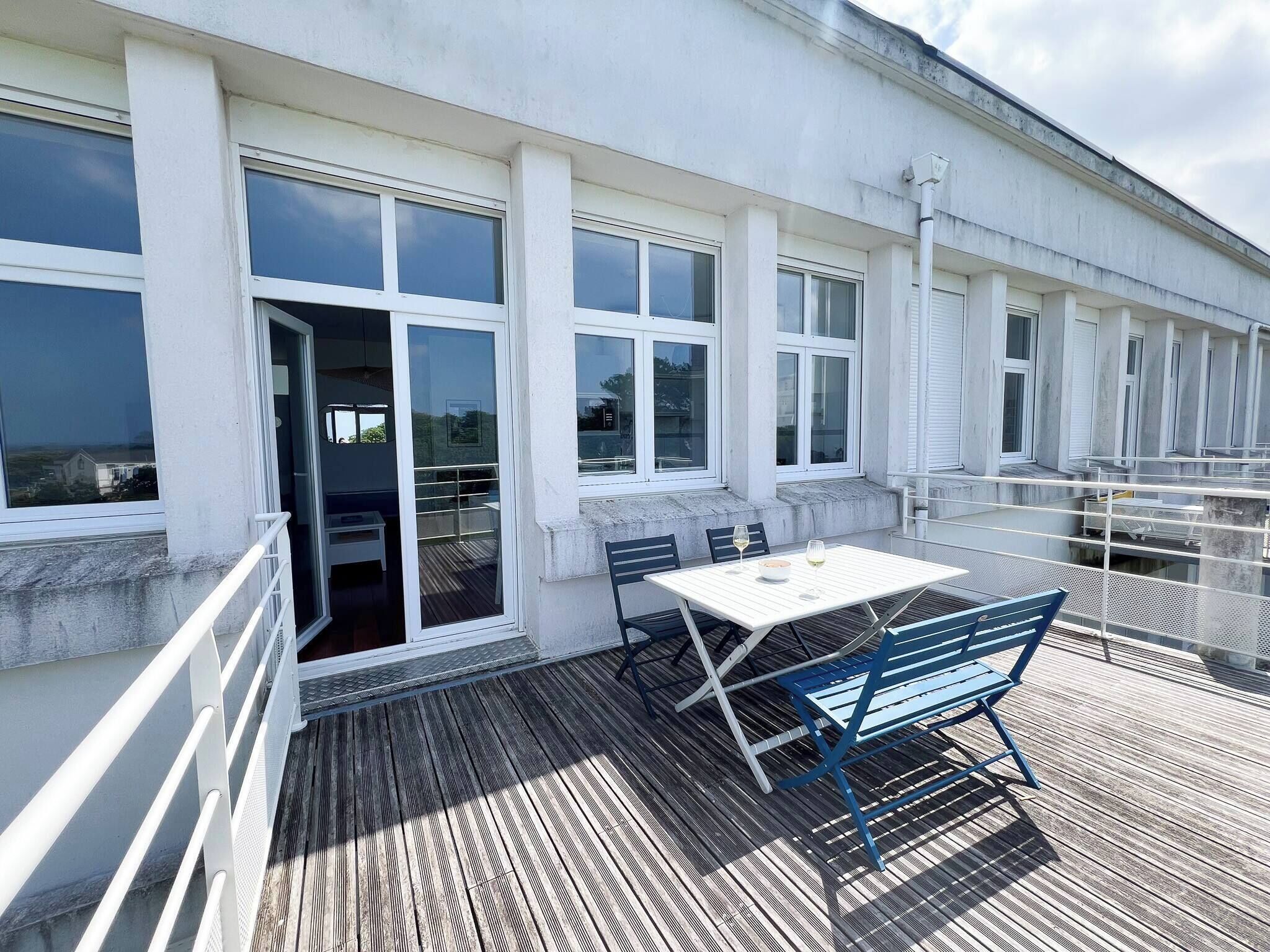 Un balcon avec une table et des chaises, donnant sur une étendue d’eau.