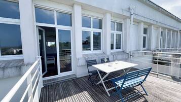 Un balcon avec une table et des chaises, donnant sur une étendue d’eau.