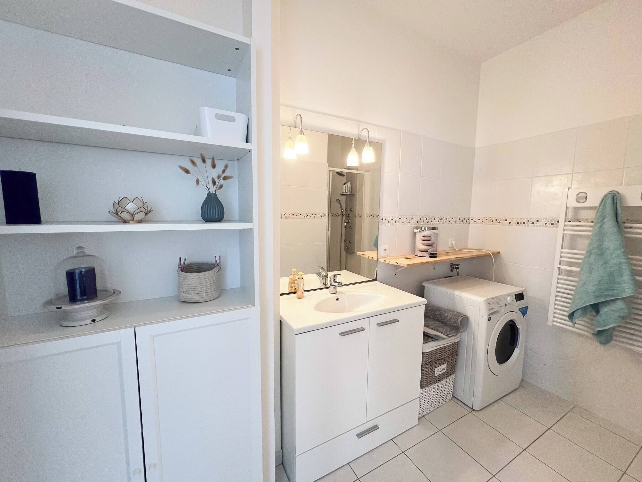Een moderne badkamer met een ingebouwd wastafel, een spiegel, een douche en een wasmachine.