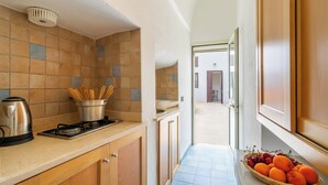A kitchen with a stove, pots, and a coffee maker. There is a window with a view of the outside. - Superior Apt - Corte dei Mesci - By Just Houses SRL (Specchia)