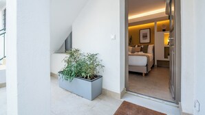 Un apartamento moderno con balcón, una planta grande en maceta y una zona de estar acogedora con cama y sofá.