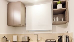 A modern kitchen with a built-in oven, a toaster, a kettle, and a coffee maker.