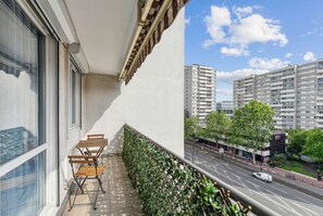Enjoy the city view from this balcony with a bench and table.