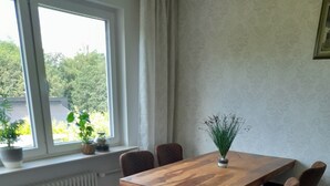 Een eetruimte met een houten tafel en stoelen, een potplant en een radiator.
