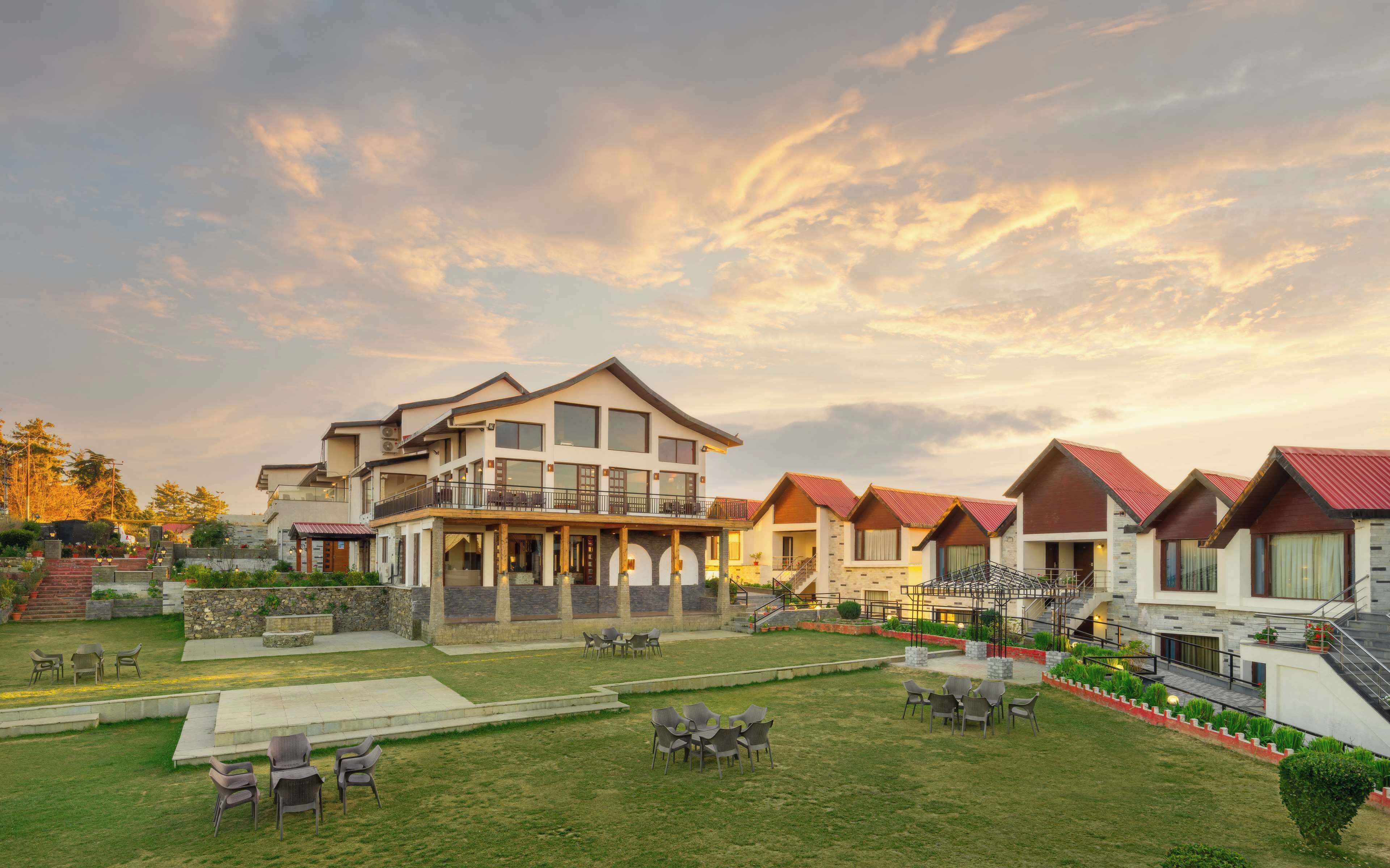 A modern hotel with multiple guest rooms, a well-maintained lawn, and outdoor seating areas.