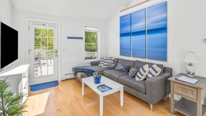 A modern living room with a grey sofa, a white coffee table, and a large blue painting on the wall. - Bright & Cozy with Patio, Grill and near the Beach & Golf (Brewster)
