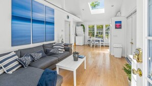 A modern living room with a grey sofa, a white coffee table, and a large blue artwork on the wall. - Bright & Cozy with Patio, Grill and near the Beach & Golf (Brewster)