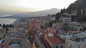 A historic town with narrow streets, traditional architecture, and a view of the sea and a mountain in the background. - Hotel Le Chevalier (Taormina)