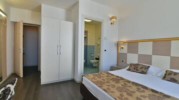 Ein Hotelzimmer mit Bett, Kleiderschrank und einem durchgegangenen Tür sichtbaren Badezimmer.