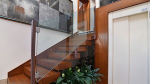 Una escalera moderna con barandillas de vidrio y peldaños de madera, que conduce a un piso superior.
