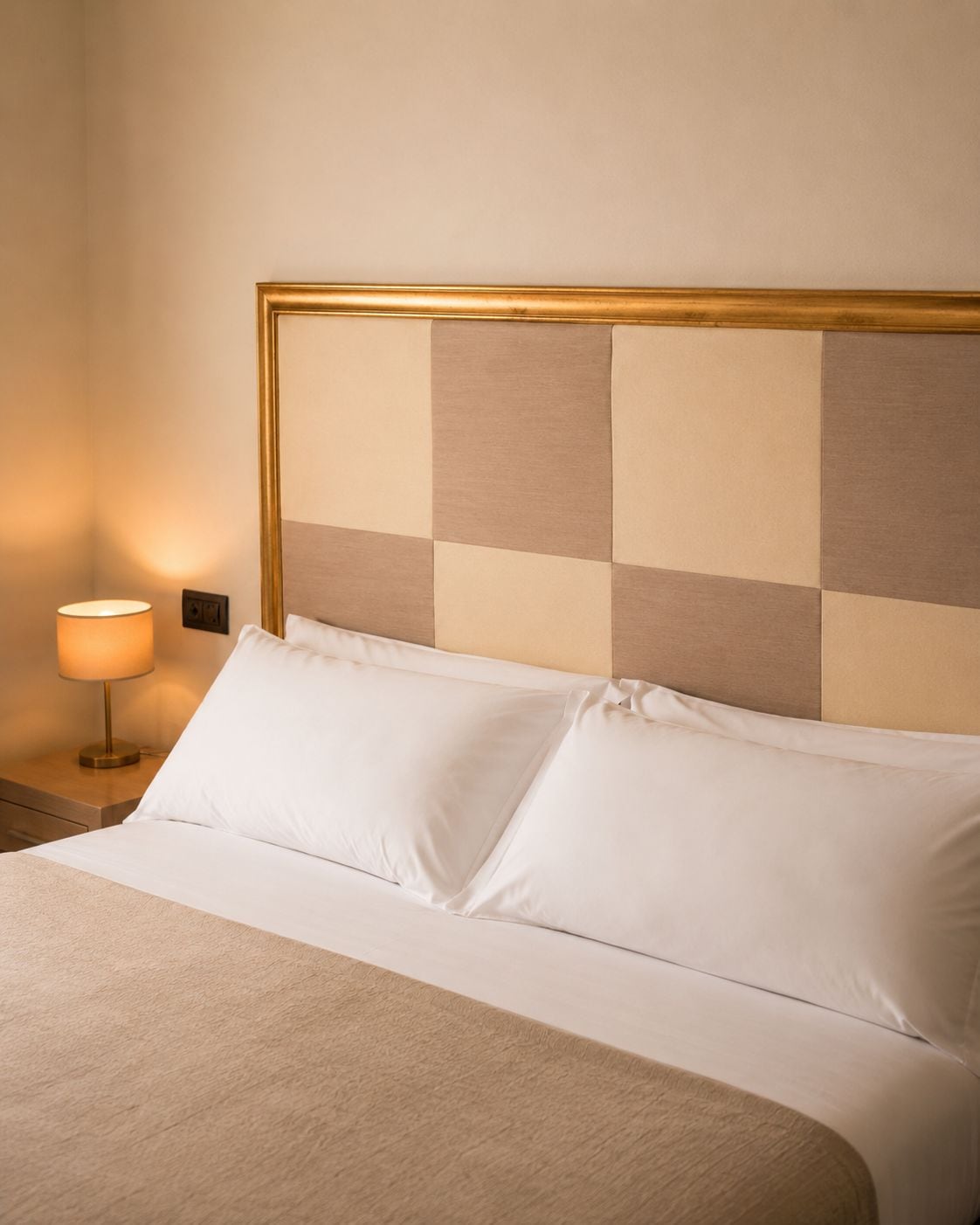 A hotel room with a bed, a nightstand, and a lamp.