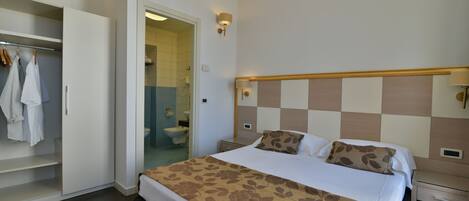 A bedroom with a bed, a wardrobe, and a bathroom visible through an open door.