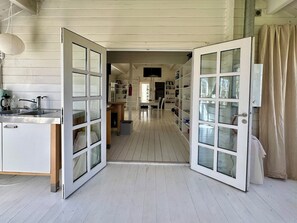 Une cuisine équipée d’un évier, un coin repas avec des chaises et une bibliothèque.