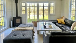 Une pièce chaleureuse avec une cheminée, un canapé, une table basse et de grandes fenêtres.